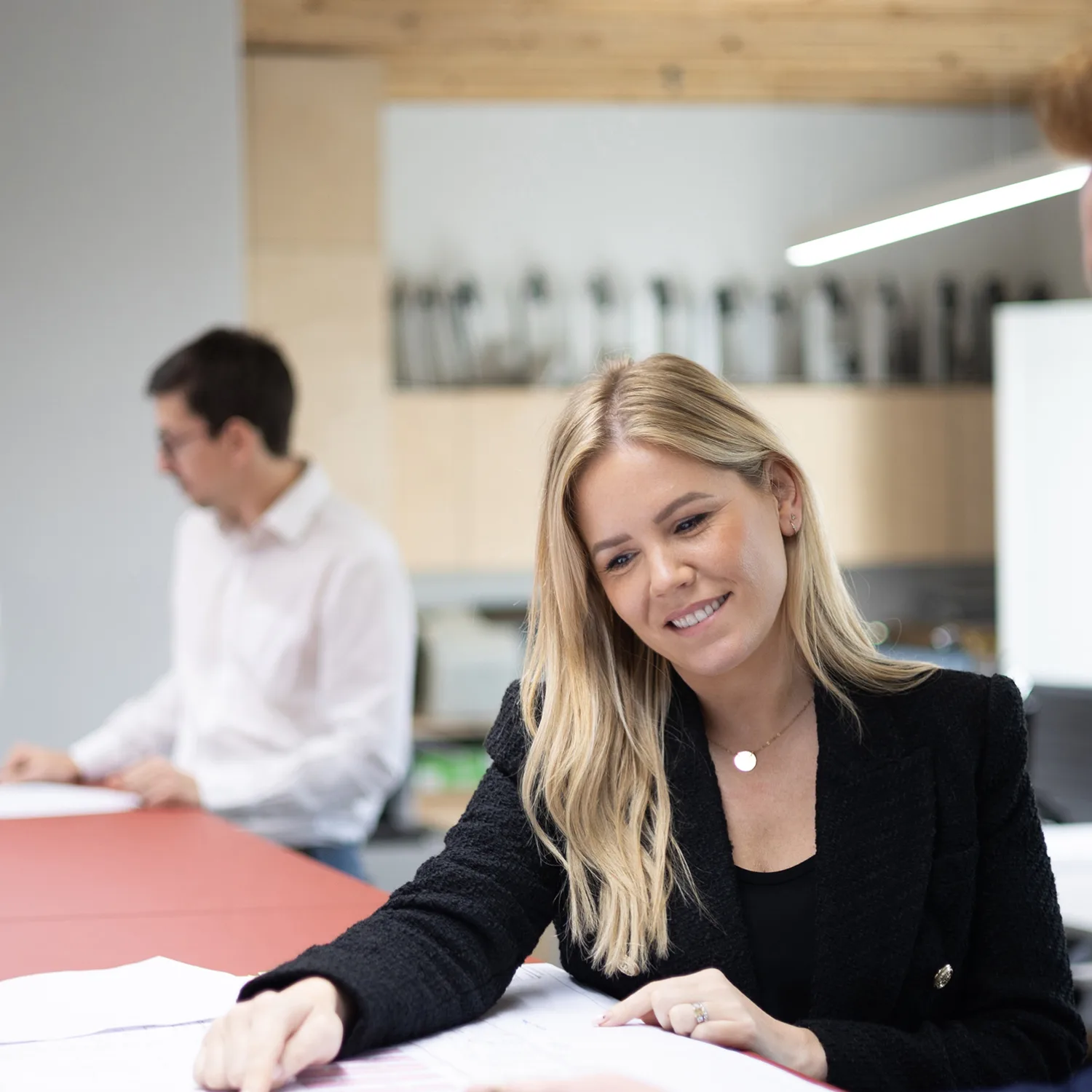 2 pairs of people discussing printed documents, one pair in the background is sightly blurred and the other is closer and in focus