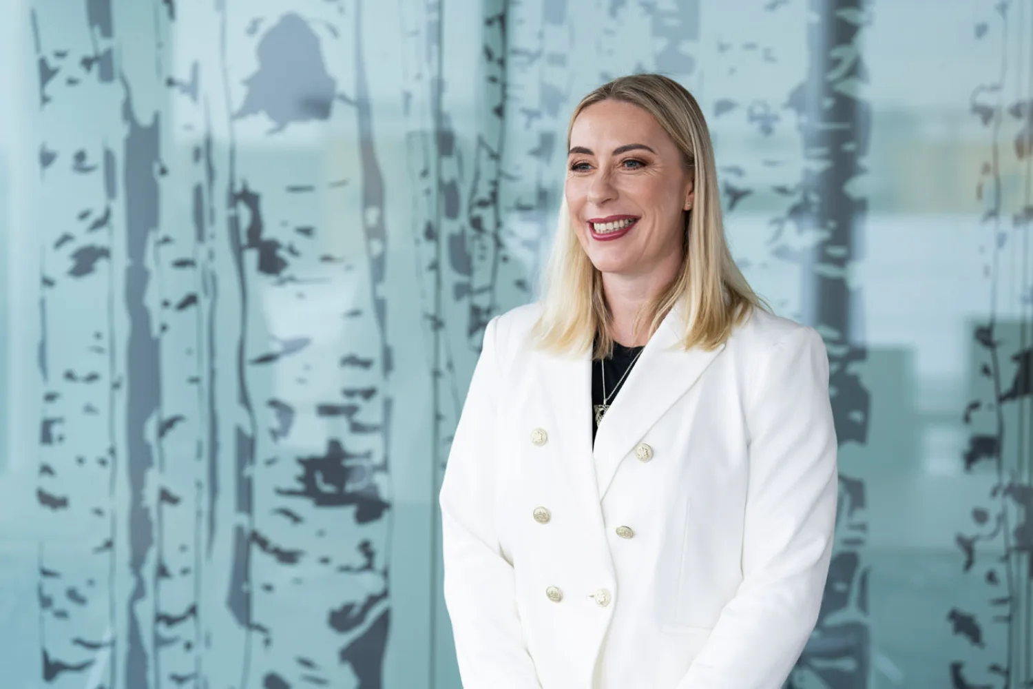 Carole looking away from camera and smiling in a white double breasted jacket