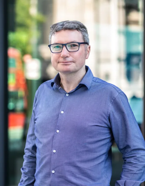 Adrian Roche with building behind with London bus reflection