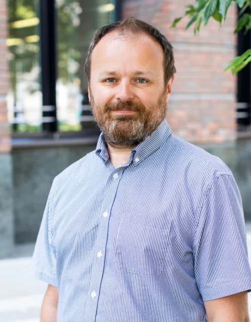 Rory Huston in front of office windows outisde in a blue shirt