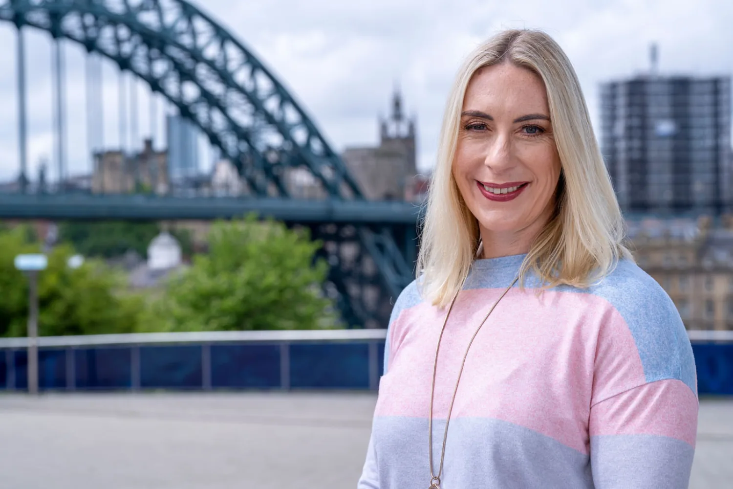 Carole in front of the Tyne Bridge smiling to camera